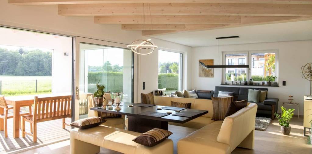 Wohnzimmer mit Essbereich und angrenzender Terrasse. naturbelassene Holzbalken an der Decke.