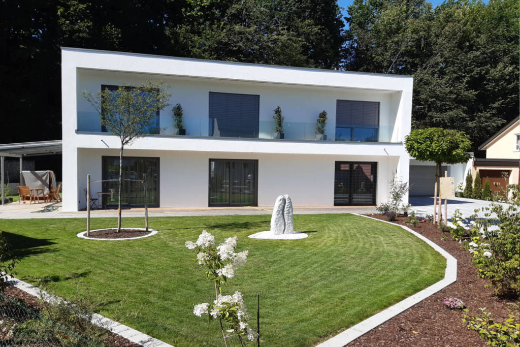 Gartenansicht: ein gepflegter Garten mit weißem modernen Haus.