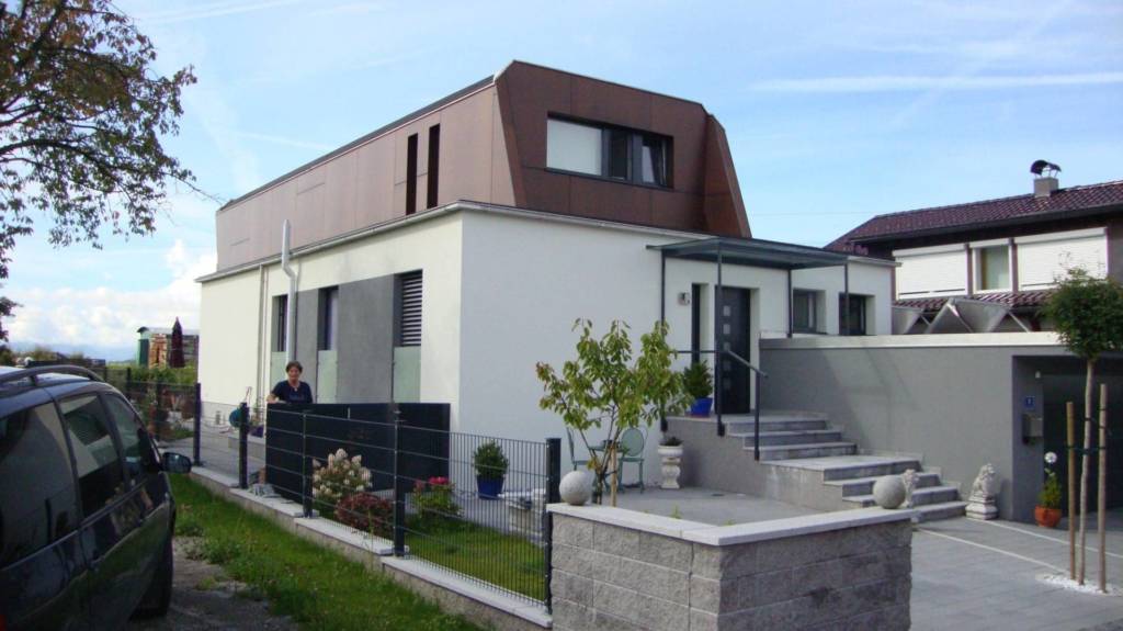 Haus mit außergwöhnlich geformten Dach und kleinem Garten.
